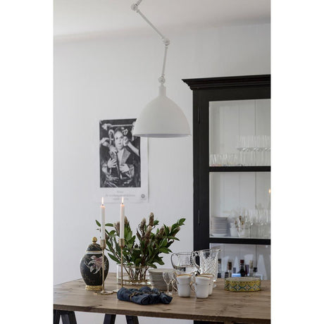 Lampada a sospensione Bazar Ø 30 cm regolabile sopra un tavolo decorato con candele e stoviglie.