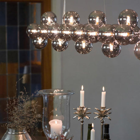 Lampada a sospensione Splendor Bar 124 cm con 24 sfere in vetro sopra un tavolo da pranzo.