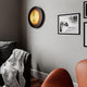 LED-vegglampe Nitra Ø 50 cm svart, gullfarget på en vegg i stuen, elegant design med varmhvitt lys.