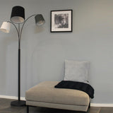 Stehlampe Foggy 3-flammig in einem modernen Raum mit einem grauen Sessel und einem Bild an der Wand.