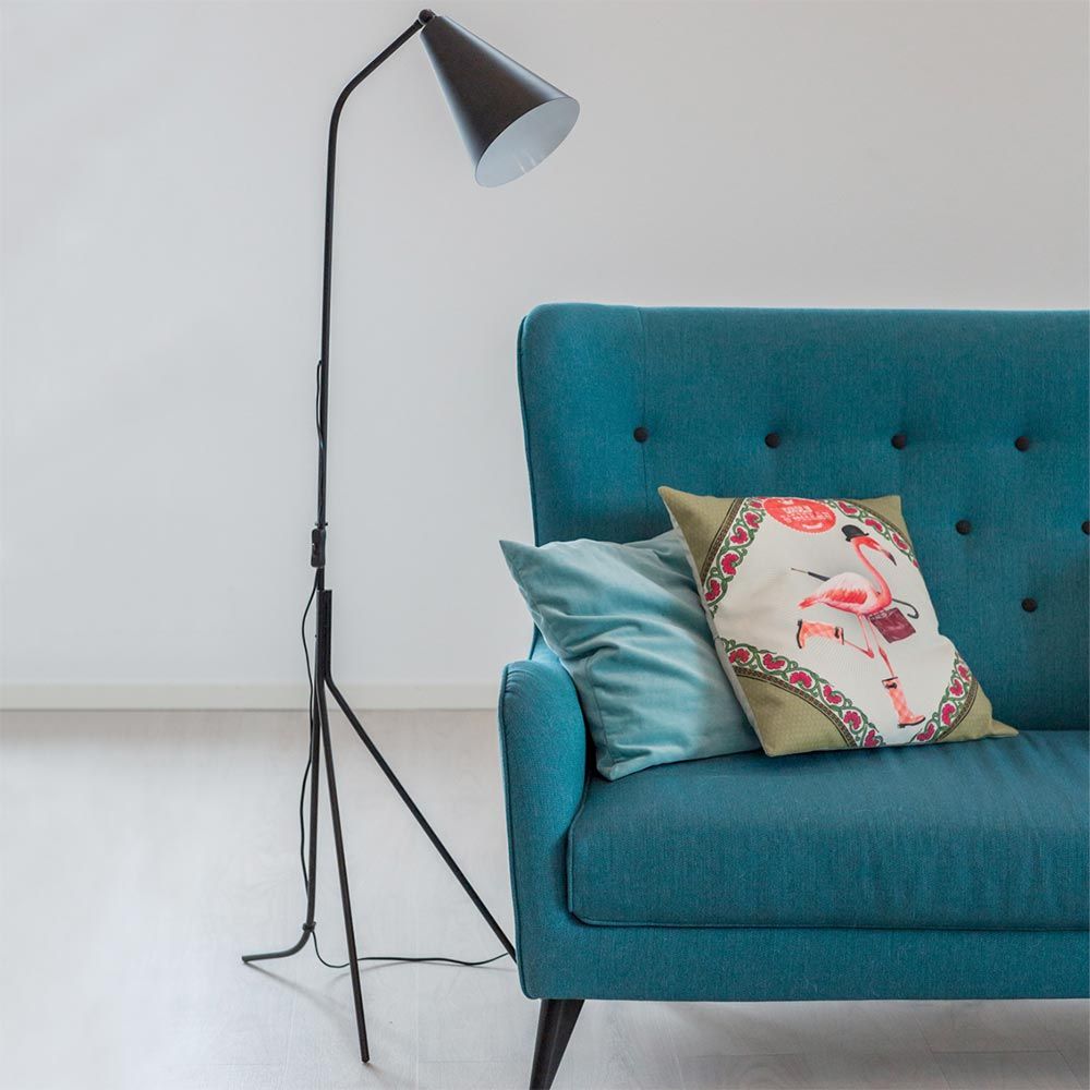 Gulvlampe Yukon treben sort ved siden av blå sofa med puter i skandinavisk stil.