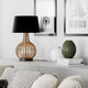 Tischlampe Granada aus Rattan mit schwarzem Baumwollschirm auf einem modernen Sideboard in stilvollem Wohnzimmer.