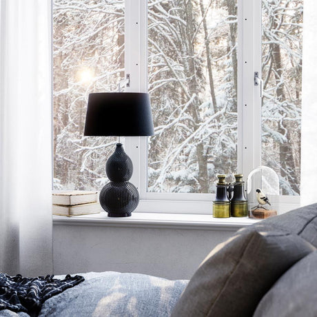 Lampada da tavolo Lofty in stile orientale su un davanzale con vista su alberi innevati.