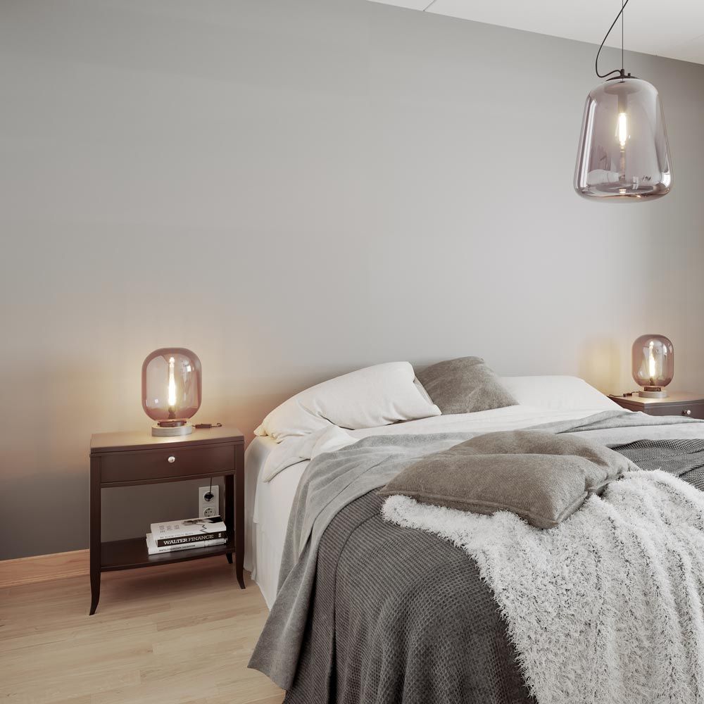 Moderne Schlafzimmeransicht mit Tischleuchte Leola aus Rauchglas, stilvollem Bett und gemütlichen Accessoires.