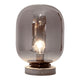 Bordlampe Leola røykglasskjerm med røykglasskjerm, matt svart metall og grå steinbase.