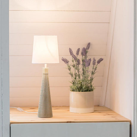 Lofty Slim table lamp with white fabric shade on a wooden shelf next to a pot of lavender.
