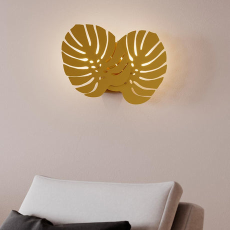 Væglampe Costa Rica messing med to Monstera blade i Art Deco stil, monteret lyst på en væg.