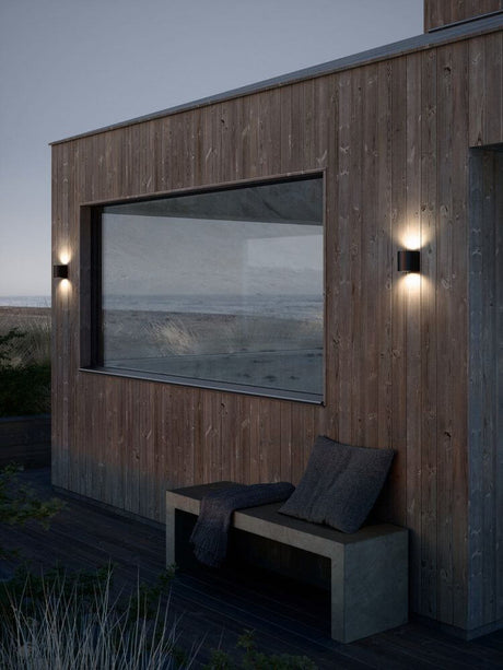 Canto 2 LED applique murale Seaside IP44 sur une façade en bois avec vue sur l’eau.