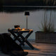 Capri USB-Tischleuchte in Schwarz auf einem Tisch am Wasser, ideal für stimmungsvolles Licht im Freien.