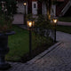 Carip Pollerleuchte Schwarz im Garten, stilvoll beleuchtet auf einem Weg, aus Stahl und klarem Glas.