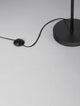 Caro Stehlampe Schwarz, Braun mit minimalistischem Fußschalter und Kabel auf hellem Boden.