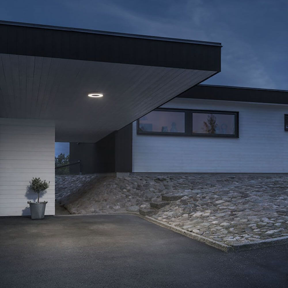 Carrara LED Außenwand- & Deckenlampe Ø 27cm CCT Weiß an einem modernen Haus in der Dämmerung.