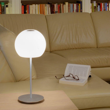Casablanca Tischleuchte Ball Big auf einem Tisch mit Buch und Brille, modernes Design in einem Wohnzimmer.