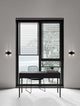 Century Wandleuchte 4-flammig Schwarz, Transparent an einer modernen Wand mit Fenster und Tisch.