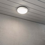 Cesena LED Buiten Wand- & Plafondlamp Rond Wit geïnstalleerd aan een grijze muur.