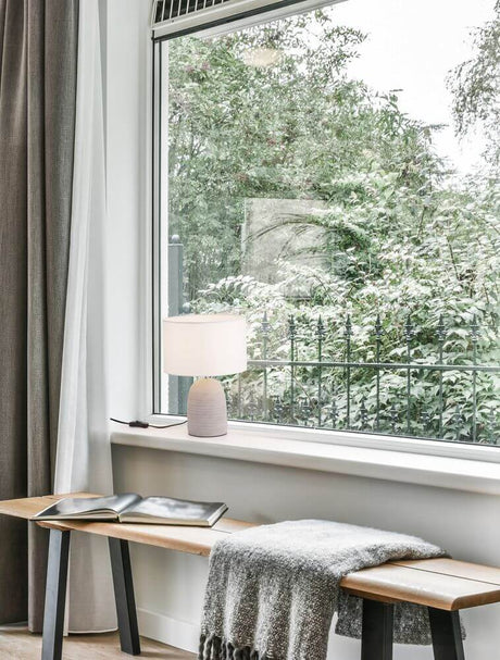 Chempo Tischleuchte Grau, Weiß auf Fensterbank in modernem Wohnraum mit Stoffschirm und Betonsockel