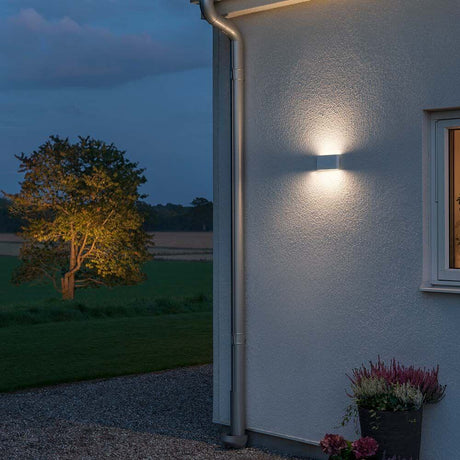 Chieri LED Applique da esterno Bianco, acrilico opalino sulla parete di una casa al crepuscolo.