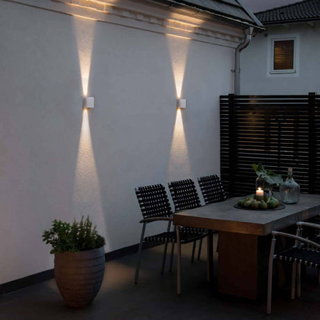 Chieri LED utendørs vegglampe Up & Downlights på en vegg i hagen med varmt lys.
