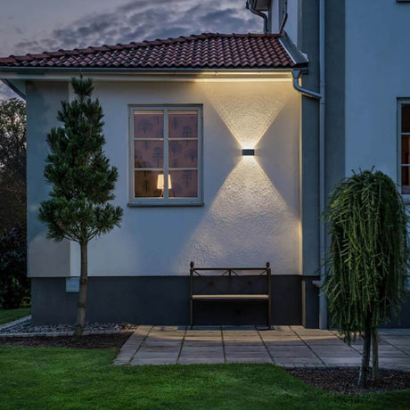 Chieri LED Außenwandleuchte an einer Hauswand, beleuchtet den Außenbereich, modernes Design in Anthrazit oder Weiß.