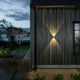 Chieri LED Wandleuchte Up & Downlights an einer Holzfassade im Freien mit warmem Licht.