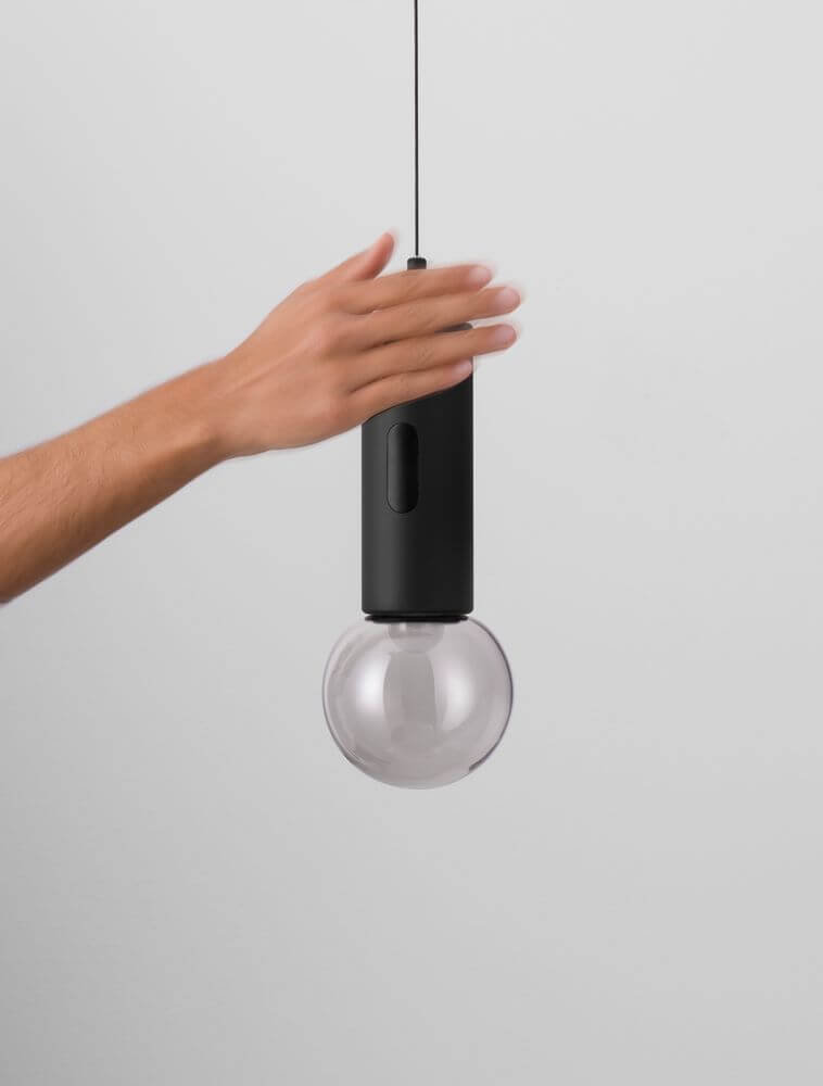 Hand hält die moderne Chronos LED Pendelleuchte 3000K mit schwarzem Gehäuse und gläserner Kugel.