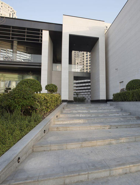 Moderne Fassade eines Gebäudes mit Treppe und Gartenanlagen, ideal für Architektur- und Design-Inspiration.