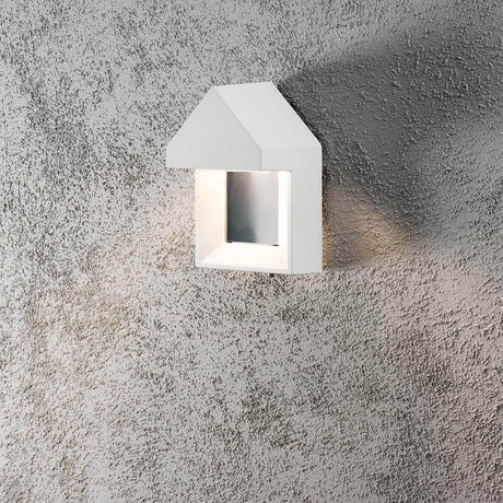Cosenza LED lampa ścienna na zewnątrz biała na szorstkiej ścianie, stylowy nowoczesny design.