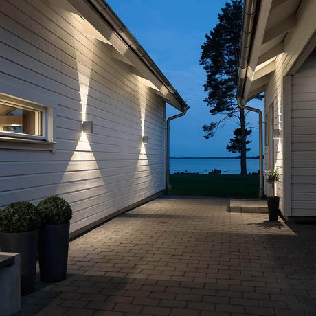 LED Cremona outdoor wall light with adjustable light output in grey on modern exterior walls at night.