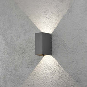 Lâmpada de parede exterior LED Cremona com saída de luz ajustável em antracite montada numa parede com raios de luz.