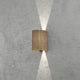 Cremona LED Messing Wandleuchte an grauer Wand strahlt nach oben und unten.