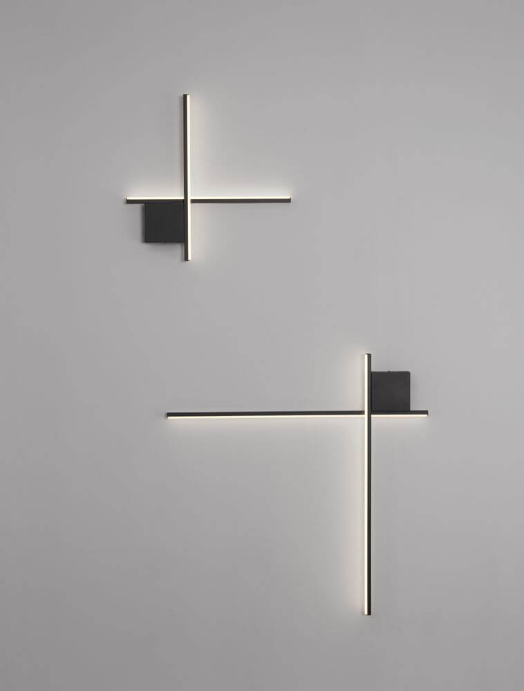 Zwei elegante Cross LED Wandleuchten in mattem Gold und Schwarz, geometrisches Design an einer grauen Wand.