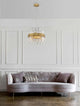 Crown Pendelleuchte 5-flammig Ø 35cm Gold-Satiniert über einem eleganten Sofa im modernen Interieur.