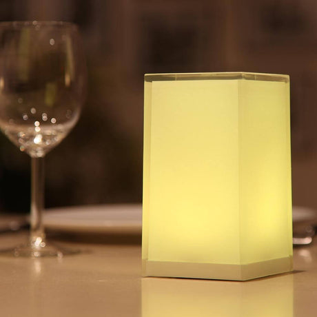 Cub USB-C accu LED-tafellamp met app-bediening op een tafel met een glas op de achtergrond.