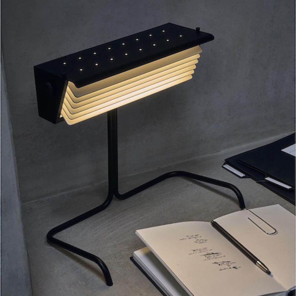 DCWéditions Biny Tischleuchte mit Lamellen auf einem Schreibtisch, ideal für gutes Leselicht.