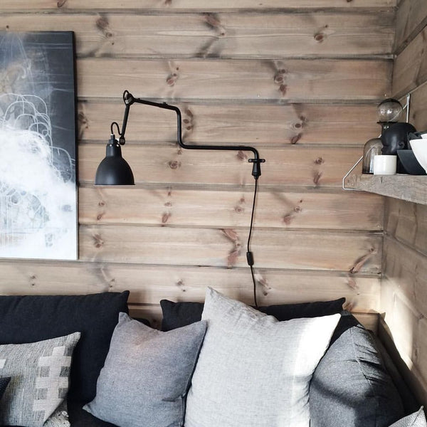 DCWéditions Gras N°303 Wandlampe mit Ausleger an Holzwand über einem Sofa