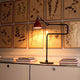DCWéditions Gras N°317 Tischlampe mit Schirm schwenkbar auf einem Tisch, beleuchtet in einem eleganten Raum.