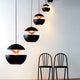 DCWéditions Here Comes The Sun Ø 18cm LED-Pendelleuchte in modernem Design über zwei schwarzen Stühlen.