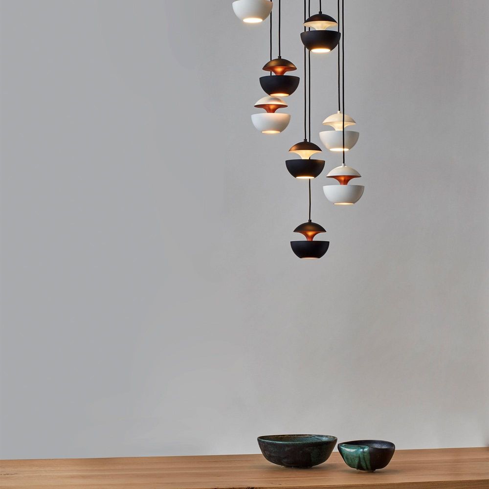 Moderne Pendelleuchten in verschiedenen Farben und Formen hängen über einem Holztablett mit dekorativen Schalen.