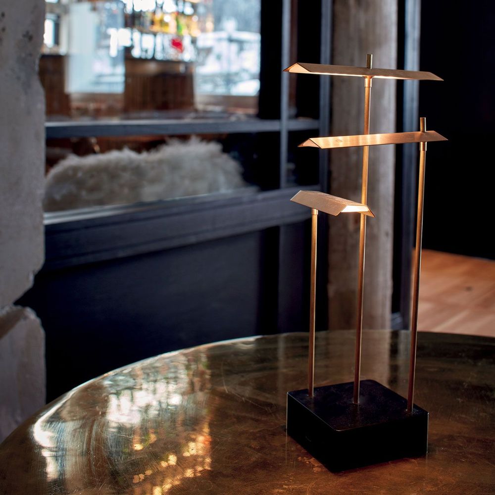 DCWéditions Knokke LED Tischleuchte in Schwarz und Gold auf einem Tisch, modern und elegant.