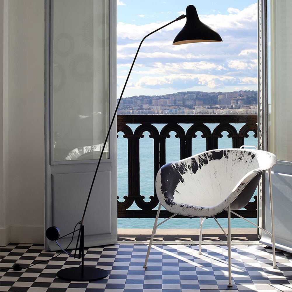 DCWéditions Mantis BS1 Stehlampe in eleganter, schwenkbarer Ausführung vor Meerblick.