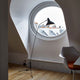 DCWéditions Mantis BS1 Leseleuchte schwenkbar neben einem runden Fenster in modernem Raumdesign.