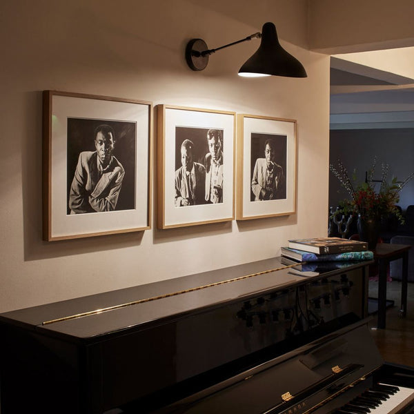 DCWéditions Mantis BS5 Wandleuchte schwenkbar Retro über einem Klavier mit Kunstwerken im Hintergrund