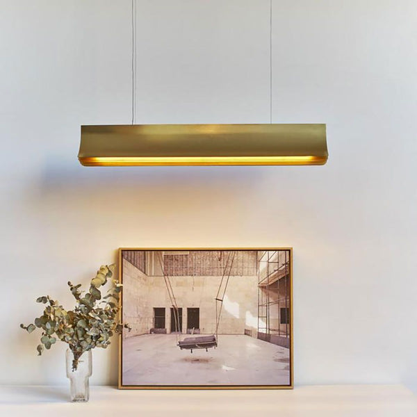 DCWéditions Respiro LED Pendelleuchte 120cm in eleganter goldener Ausführung über minimalistischer Dekoration.