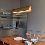 DCWéditions Respiro LED Pendelleuchte 90cm in moderner Kücheneinrichtung mit Holzstühlen und Geschirr.