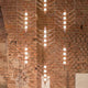 DCWéditions VVV Abhängung Baldachin für Module mit modernen Lichtdesigns an einer Backsteinwand.