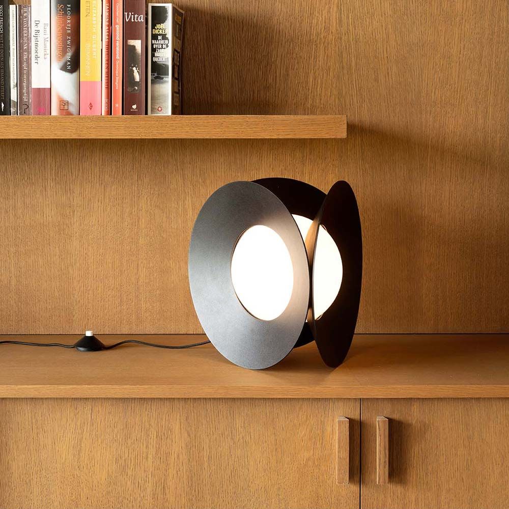 DCWéditions Armen LED Tischleuchte in Matt-Schwarz auf Holzregal, inspiriert von geometrischen Formen.