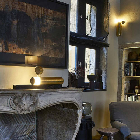 DCWéditions ISP LED marmor bordlampe messinglakkert på en peishylle i et moderne interiør