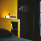DCWéditions ISP LED Tischleuchte aus Messing auf Marmorsockel in modernem Schlafzimmer mit gelber Wand.