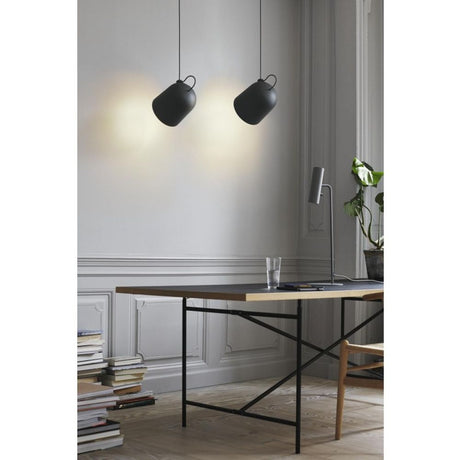 LED Pendelleuchte Angle Schwarz über einem modernen Tisch in einem stilvollen Raum.