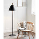 Stehlampe Strap Schwarz in modernem Interieur neben einem Holzstuhl mit Decke.